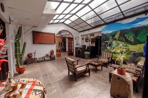 Um quarto espaçoso com teto alto, claraboia de vidro, um mural e uma mesa de recepção.