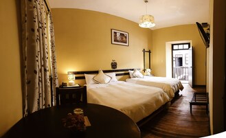 A hotel room with two beds, a nightstand with a lamp, a framed picture on the wall, and a view of the outside balcony.