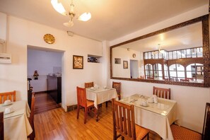 A dining area with wooden flooring, a large mirror, and a view of the outside through large windows. - Yabar Hotel Plaza (Cusco)