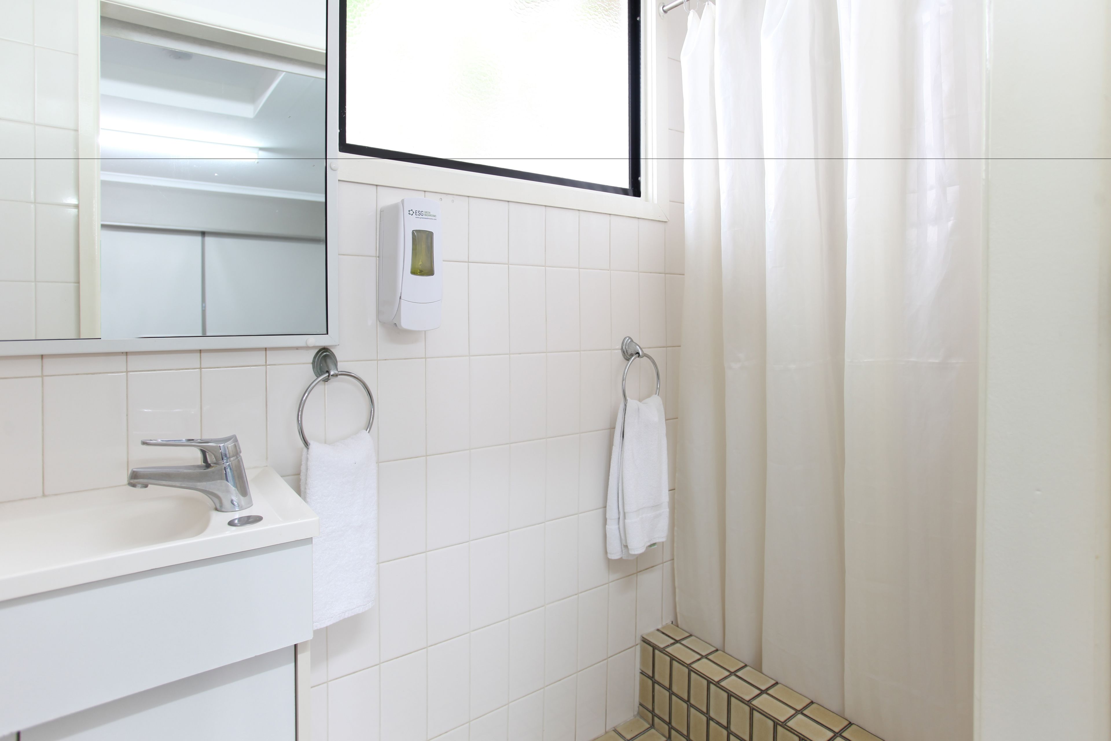 A bathroom with a white sink, a mirror, a towel rack, and a shower curtain.
