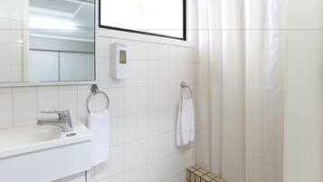 A bathroom with a white sink, a mirror, a towel rack, and a shower curtain.