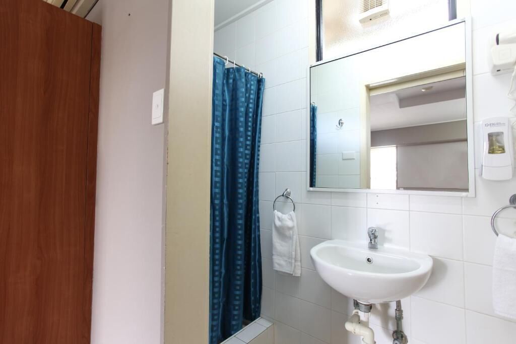A bathroom with a white sink, a mirror, and a blue shower curtain.