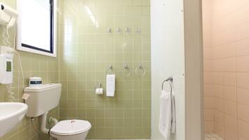 Un baño con inodoro, lavabo y zona de ducha.
