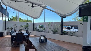 An outdoor patio with wooden tables and chairs, a ceiling fan, string lights, and potted plants. - Tandara Hotel Motel (Sarina)