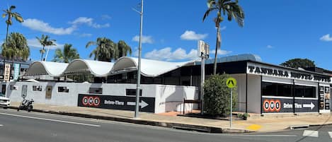 Um edifício com placas indicando 'Tandara Motel Hotel' e 'BWS Drive-Thru', mostrando um serviço de drive-thru.