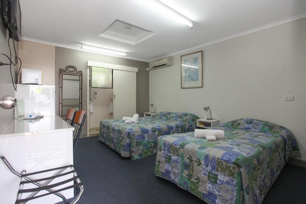 Una camera d'albergo con due letti, una scrivania e una sedia.