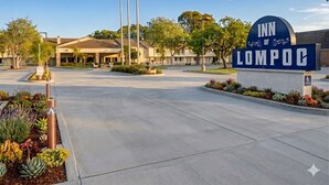 The entrance to the Inn of LompoC with a clear pathway, American flags, and a sign indicating handicap accessibility. - Inn of Lompoc (Lompoc)