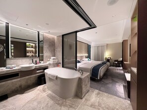 A modern hotel bathroom with a large bathtub, a vanity with a mirror, and a separate shower area.