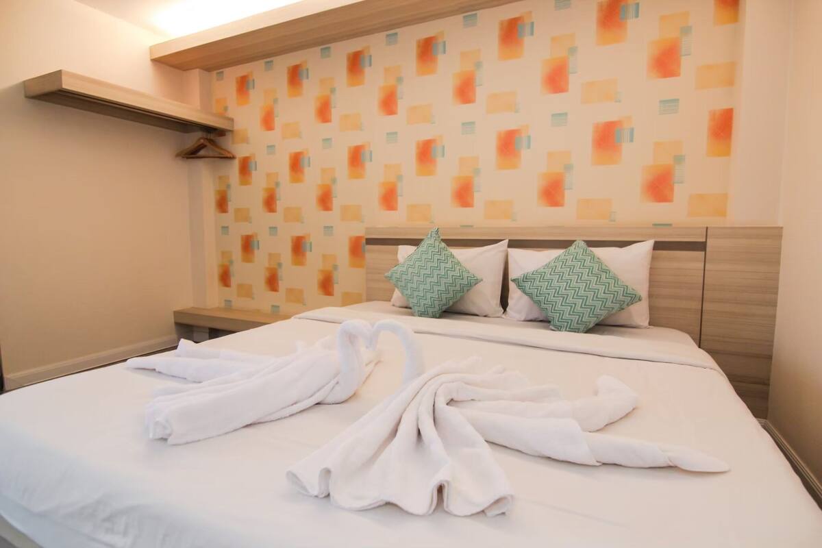 Une chambre d’hôtel avec un lit bien fait, deux oreillers et une serviette joliment disposée sur le lit.