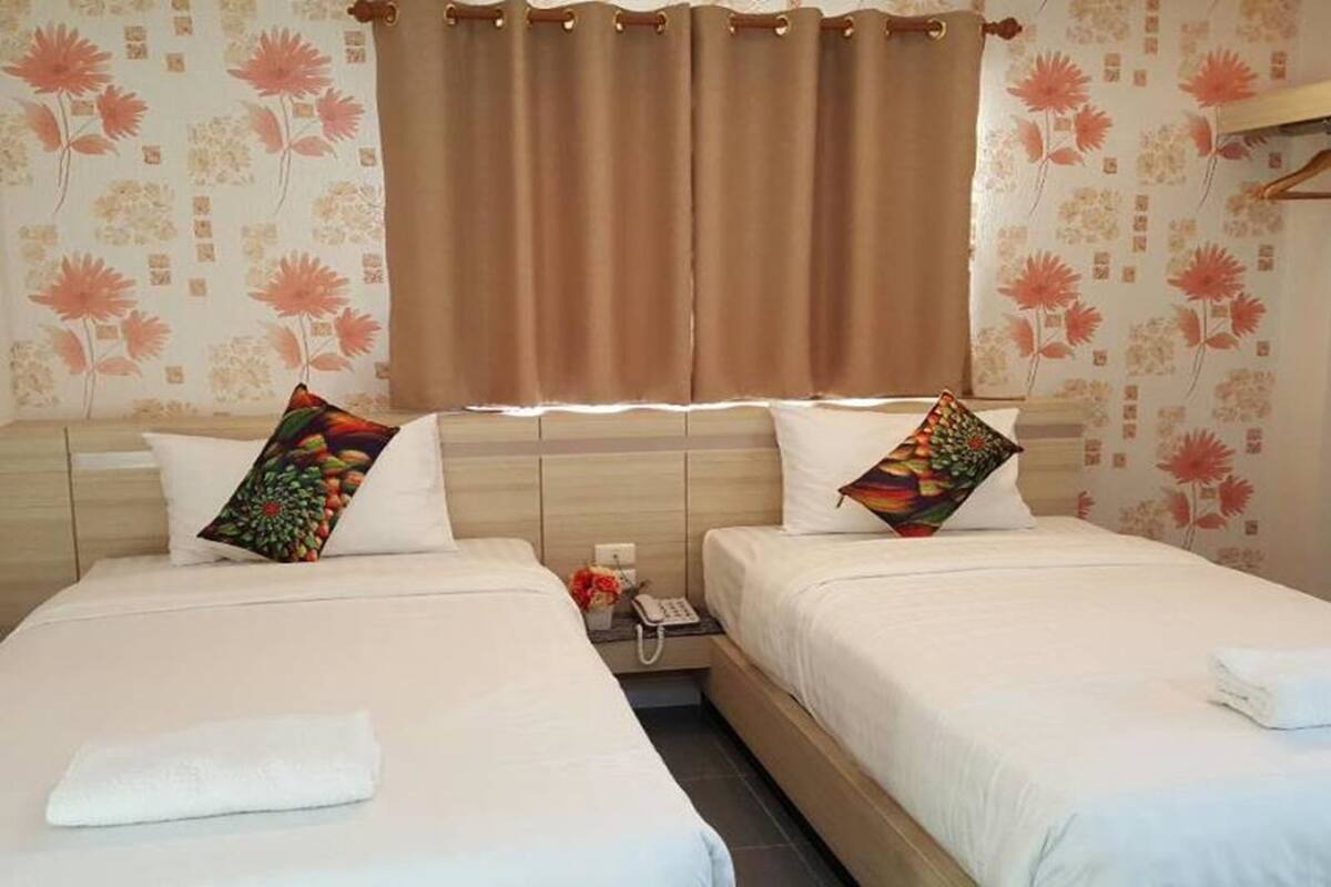 Une chambre d’hôtel avec deux lits, un téléphone et une table de chevet avec une lampe.