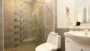 Ein modernes Badezimmer mit einer Duschkabine, einer weißen Toilette und einem Waschbecken mit Spiegel darüber.