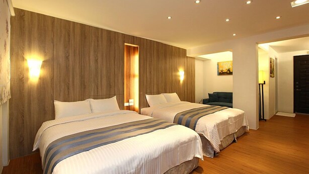 Ein Hotelzimmer mit zwei Betten, Holzvertäfelung und einer kleinen Sitzecke.