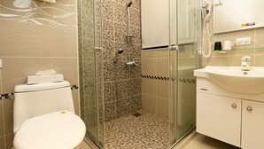 Ein Badezimmer mit einer Duschkabine, einer Toilette und einem Waschbecken mit Spiegel darüber.