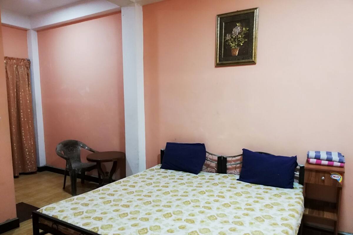 A bedroom with a bed, a chair, a nightstand, and a framed picture on the wall.