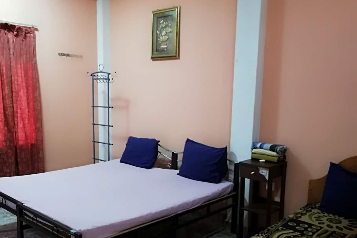 A bedroom with a bed, a small table, a chair, and a wardrobe.