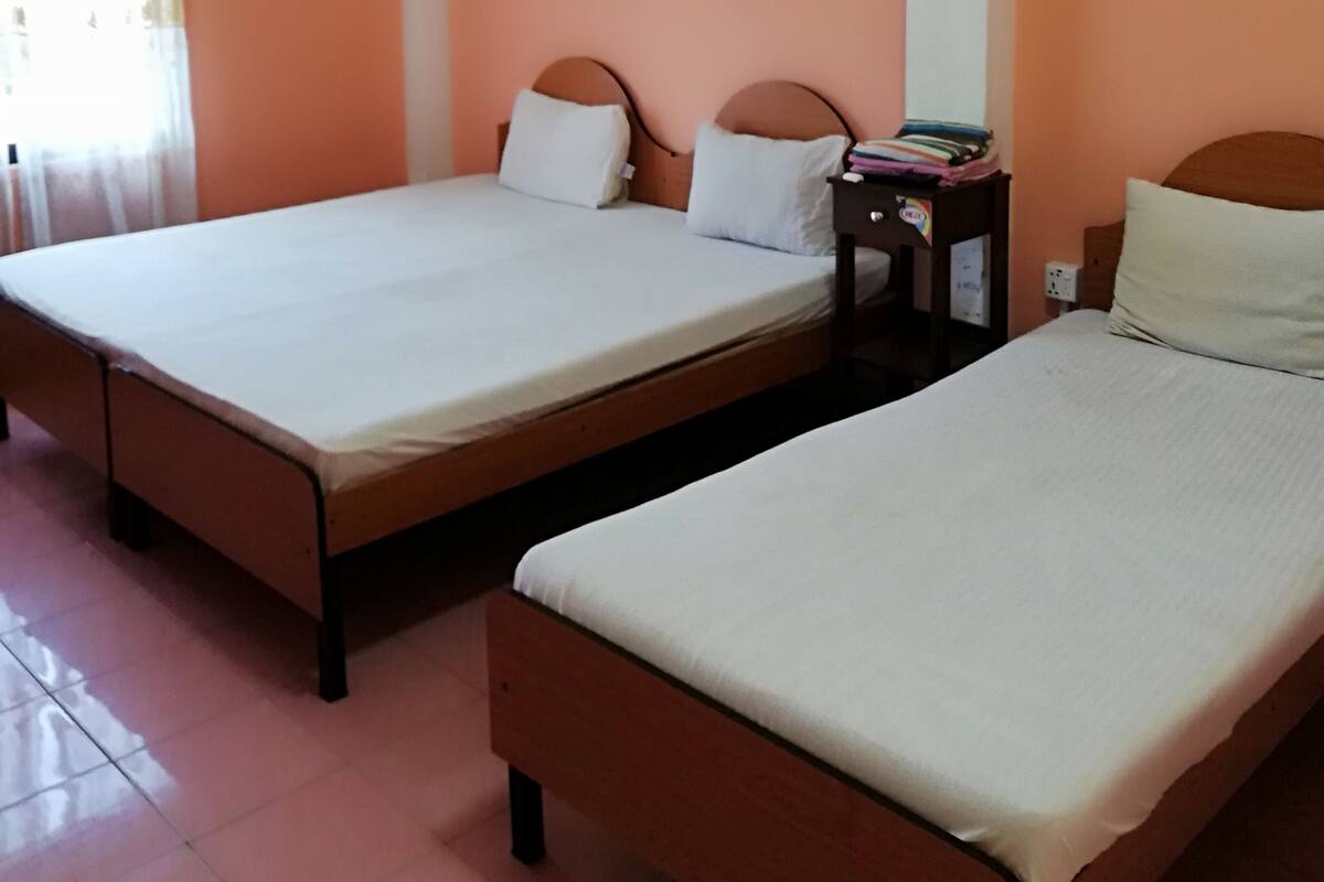 A room with two beds, a ceiling fan, an air conditioning unit, and a framed picture on the wall.