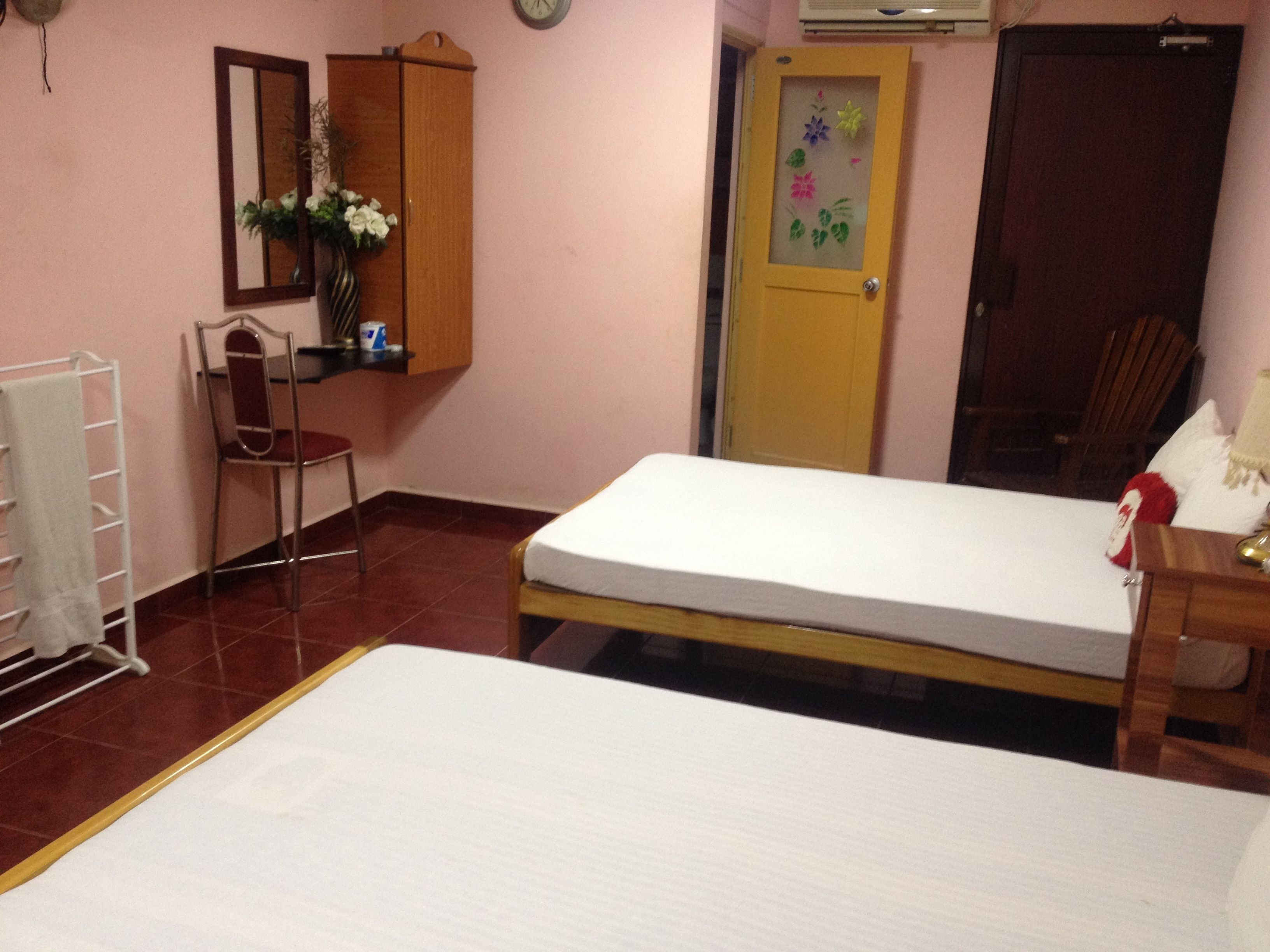 A bedroom with a bed, a chair, a desk, a mirror, a wardrobe, and a door with a floral decoration.
