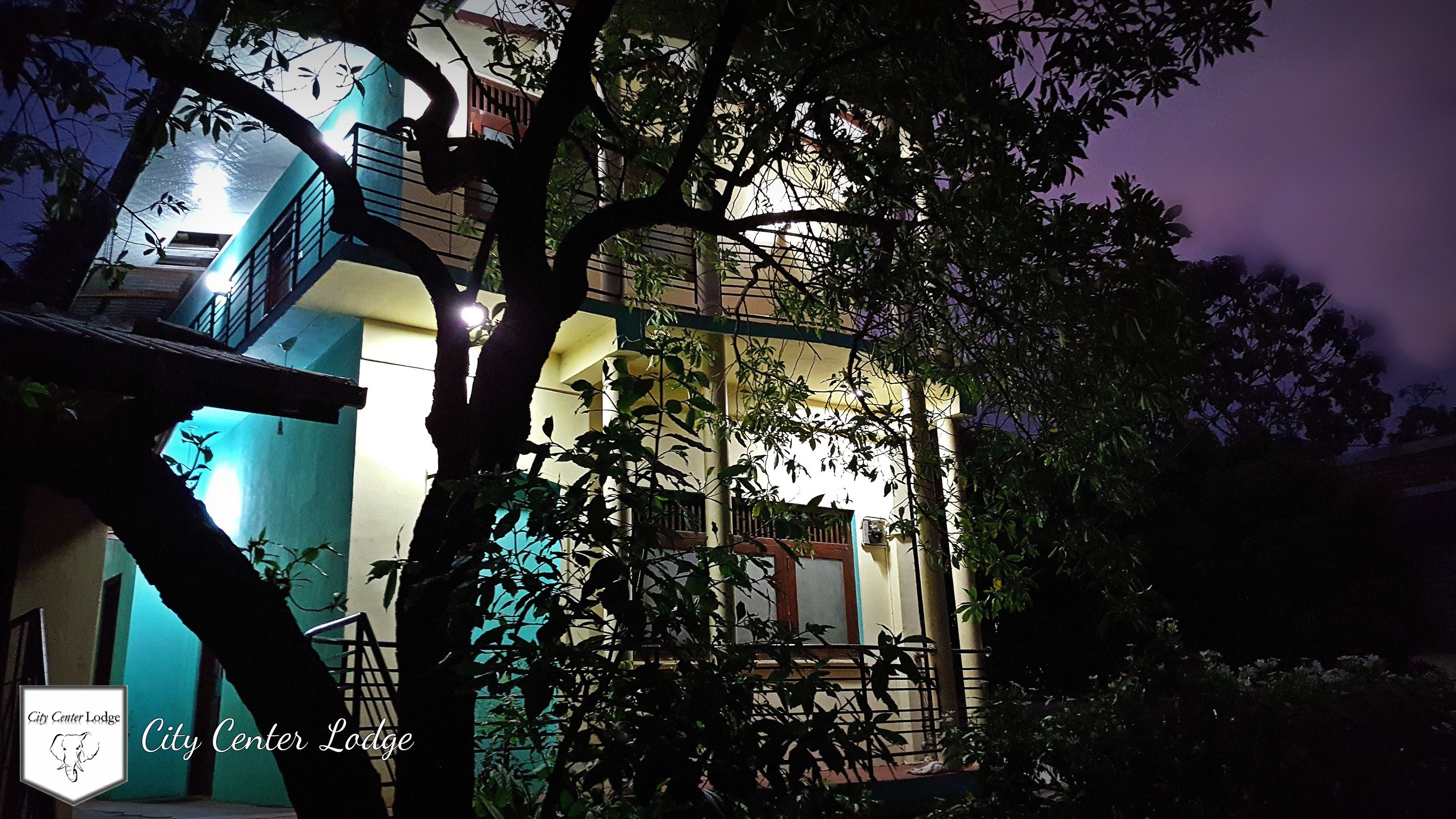 Un edificio con balcón y escalera, rodeado de árboles.