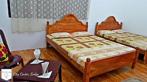 Una habitación con dos camas de madera, una mesita con un vaso y una servilleta, y una silla con un cojín de colores.