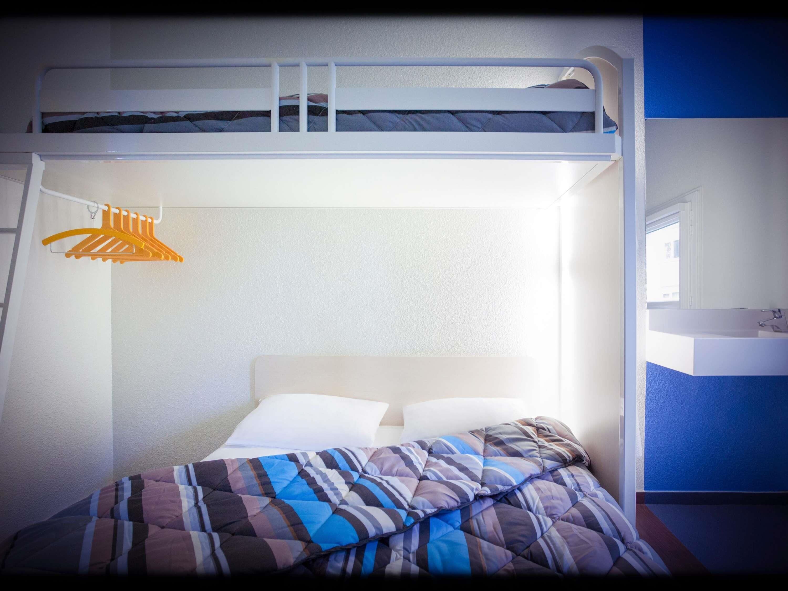 A bunk bed with a white headboard, a hanging orange hanger, and a blue wall.