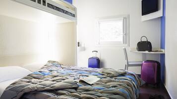 Una habitación de hotel con una cama litera, una maleta, una silla, un televisor y una ventana.