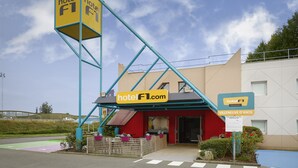 Un hôtel reconnaissable à son enseigne bleue et jaune, à son entrée rouge et à son parking doté d’une piste cyclable verte.