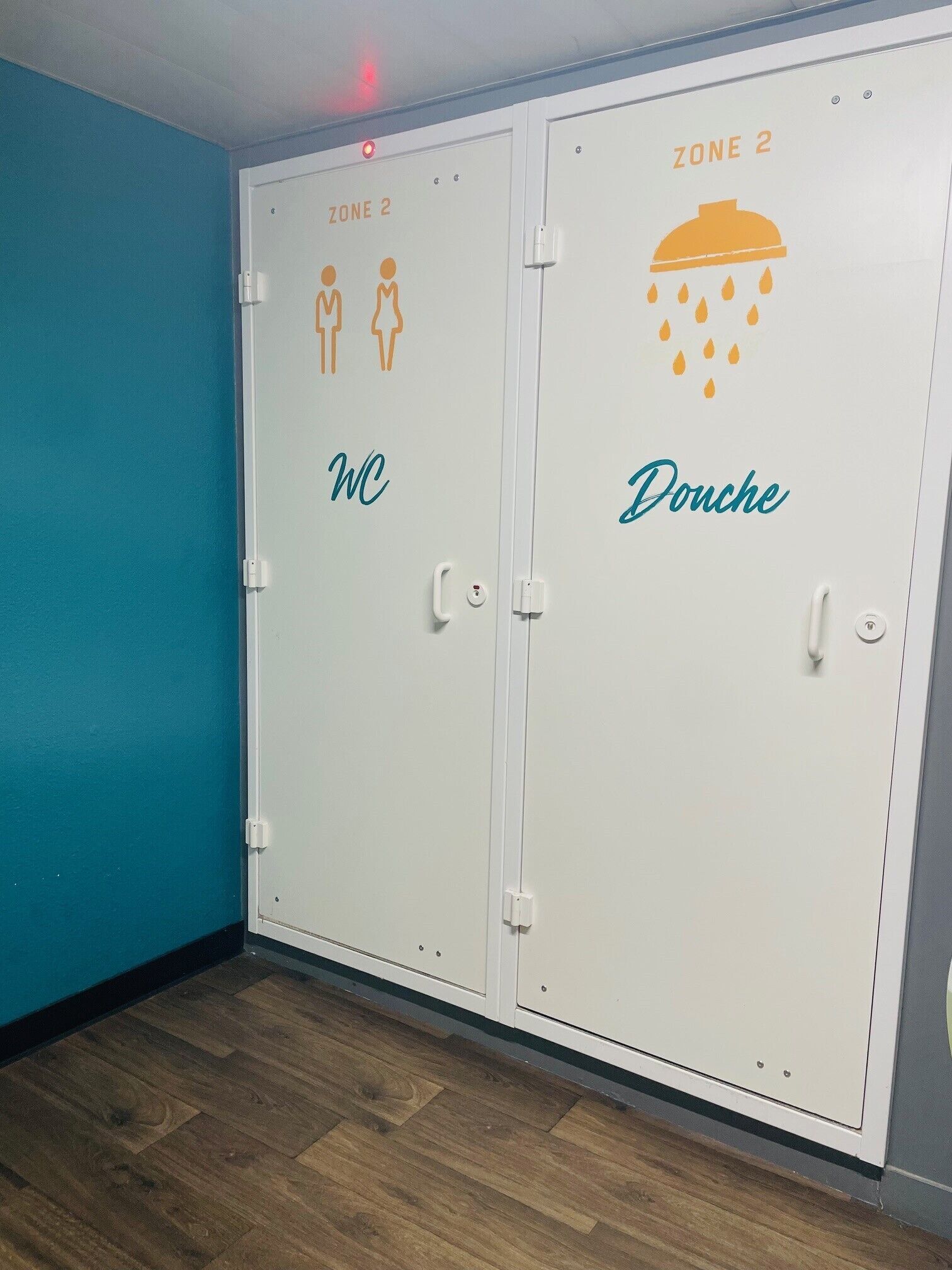 A set of two doors labeled "ZONE 2 WC" and "Douche" with icons indicating facilities.