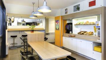 Una cocina moderna con una mesa de madera, taburetes de bar y una encimera con alimentos.