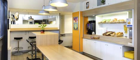 A modern kitchen with a wooden table, bar stools, and a counter with food items.