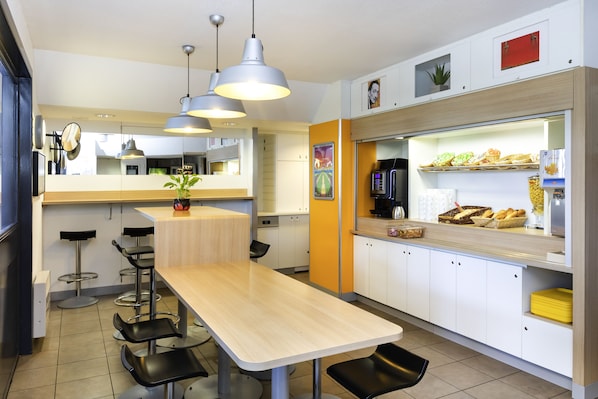 Une cuisine moderne avec une table en bois, des tabourets de bar et un comptoir où sont disposés des aliments.