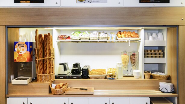 Un buffet de petit-déjeuner d’hôtel avec du pain, des viennoiseries et des machines à café.