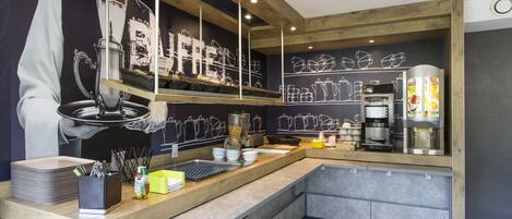 A modern kitchen with a wooden countertop, a coffee machine, and a chalkboard wall with kitchen utensils.