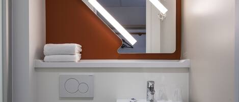 A bathroom with a white sink, a mirror, and a towel on the counter.