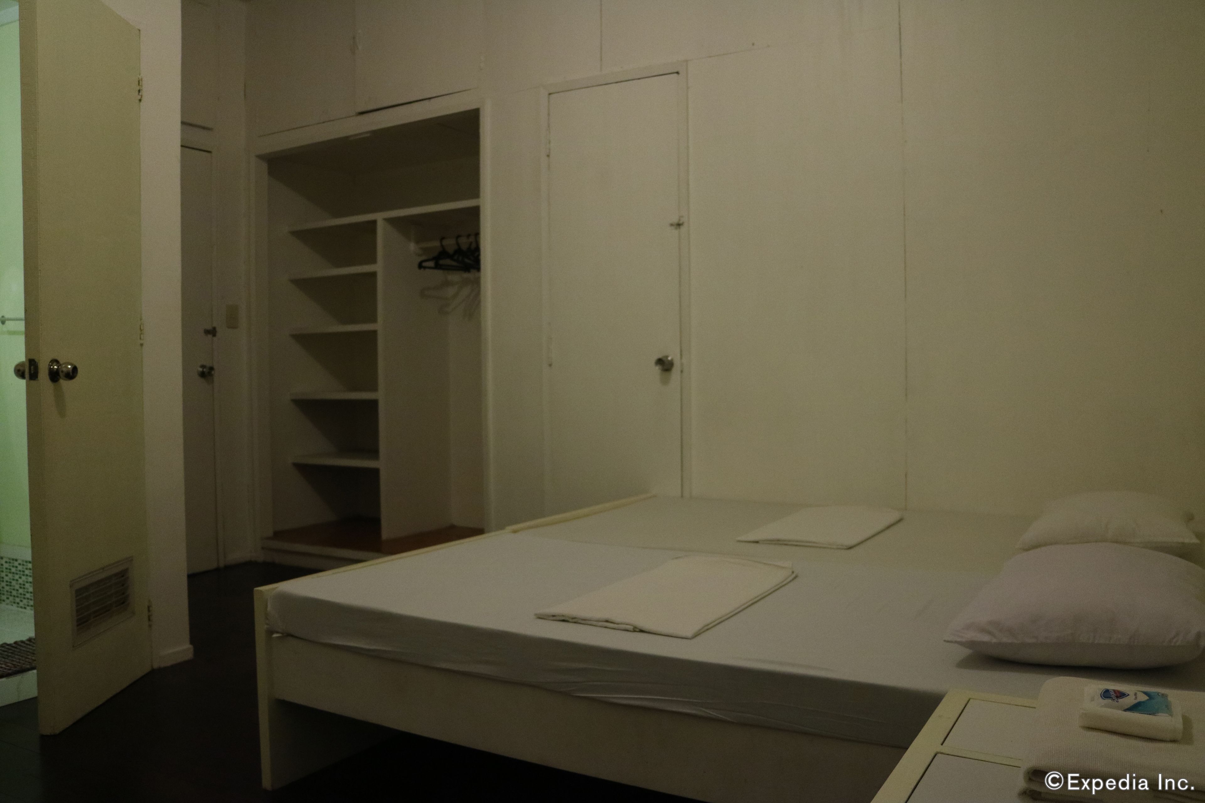 Une petite chambre avec un lit simple, un placard et une porte donnant sur une salle de bain.