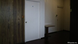 Un couloir avec un mur lambrissé en bois, une porte blanche portant le numéro 6 et une petite table.