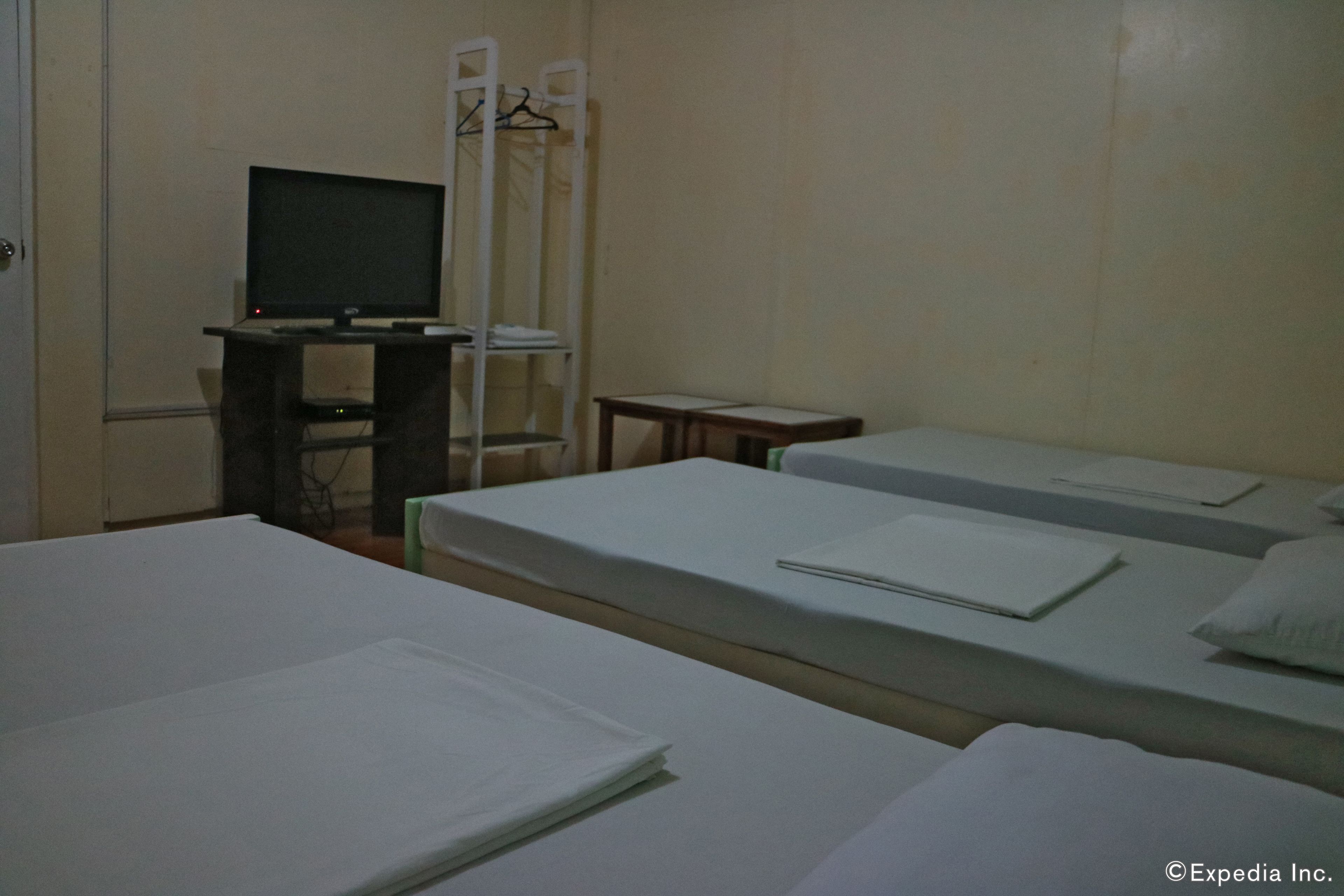 Quarto de hotel com duas camas, uma escrivaninha com televisão e uma cadeira.