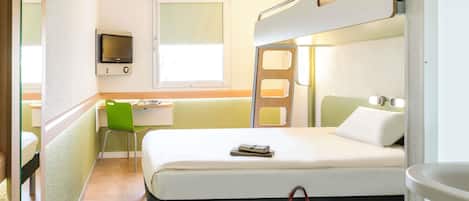 Una habitación de hotel con una cama, un escritorio, una silla, un televisor y un baño.