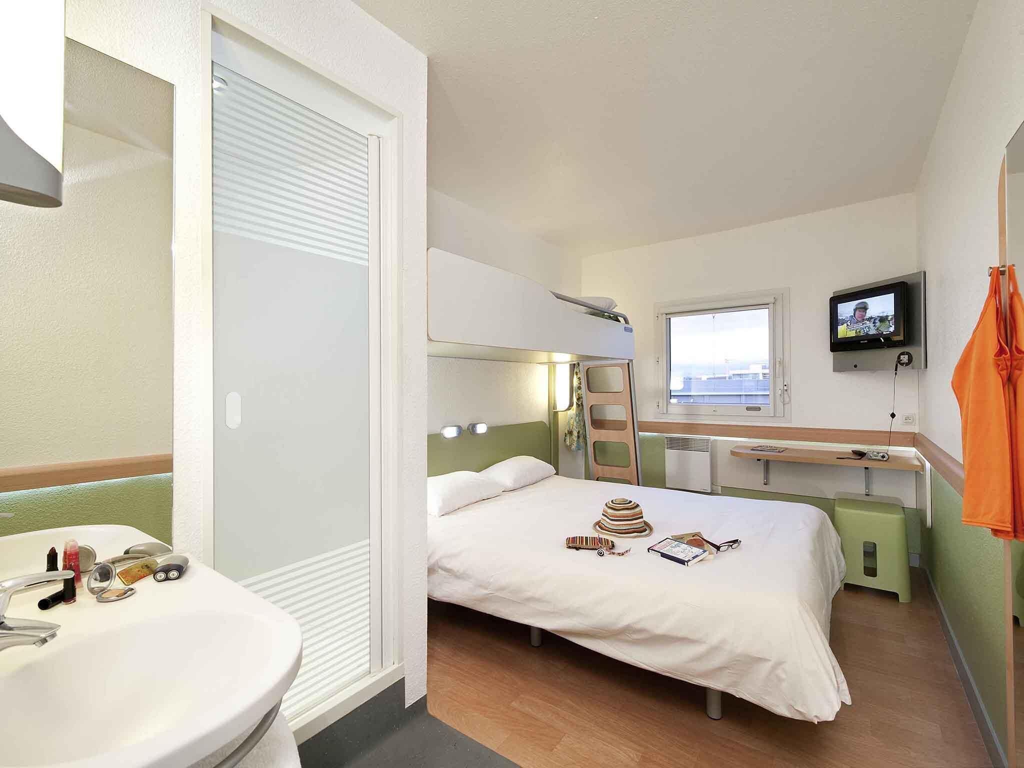 Ein Hotelzimmer mit Bett, Fernseher, Schreibtisch und Bad.
