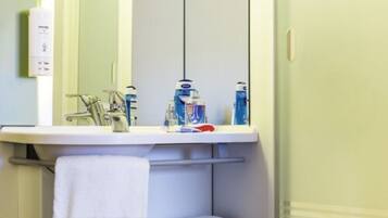 A bathroom with a sink, mirror, towel rack, and toiletries.