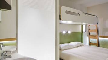 Una habitación de hotel pequeña con una litera, un lavamanos y un espejo.