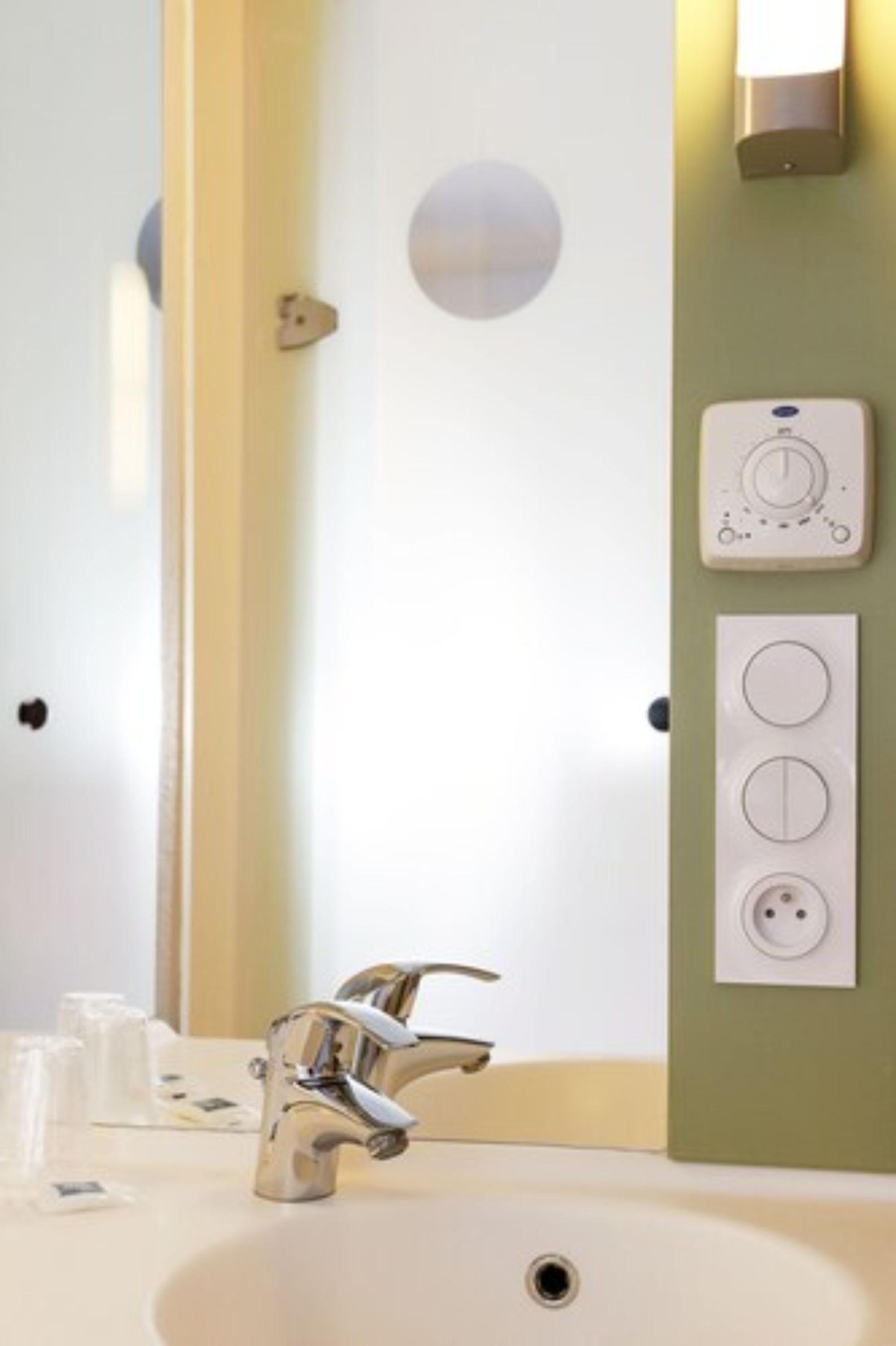 A bathroom with a modern sink, a mirror, and a wall-mounted light fixture.