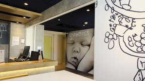 Un área de recepción con mostrador, computadora y pared con un gran dibujo blanco y negro.
