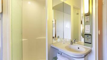 Une salle de bain moderne avec un lavabo blanc, un miroir et une cabine de douche en verre.