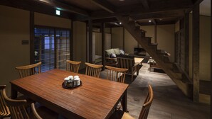 Ein traditioneller japanischer Raum mit einem Holzespeisetisch, Stühlen und einer Treppe.