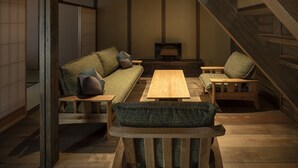 Ein traditioneller japanischer Raum mit Tatami-Böden, einem niedrigen Holztisch und einer Couch mit Kissen.