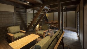 Ein gemütliches Interieur mit einer Holztreppe, einer Sitzecke und einem Esstisch.