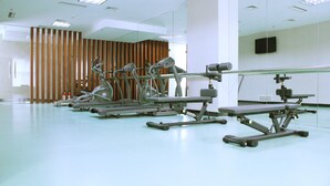 A gym with exercise equipment, a mirror, and a wooden partition. - Tian Feng International Hotel (Shenyang)