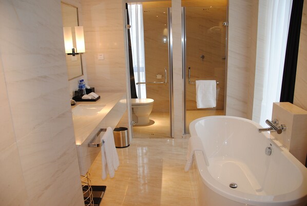 A modern bathroom with a large bathtub, a glass-enclosed shower, and a toilet. - Tian Feng International Hotel (Shenyang)