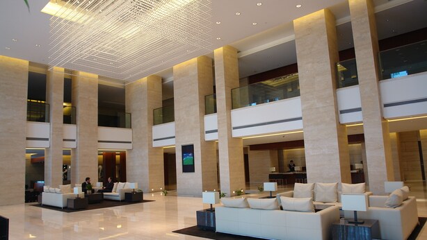 A spacious lobby with high ceilings, large columns, and modern seating arrangements. - Tian Feng International Hotel (Shenyang)