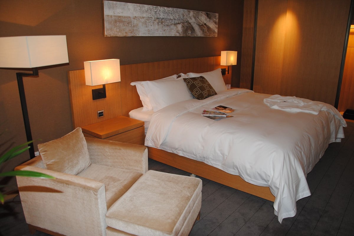 A hotel room with a large bed, two bedside tables with lamps, a chair, and a wall-mounted artwork.